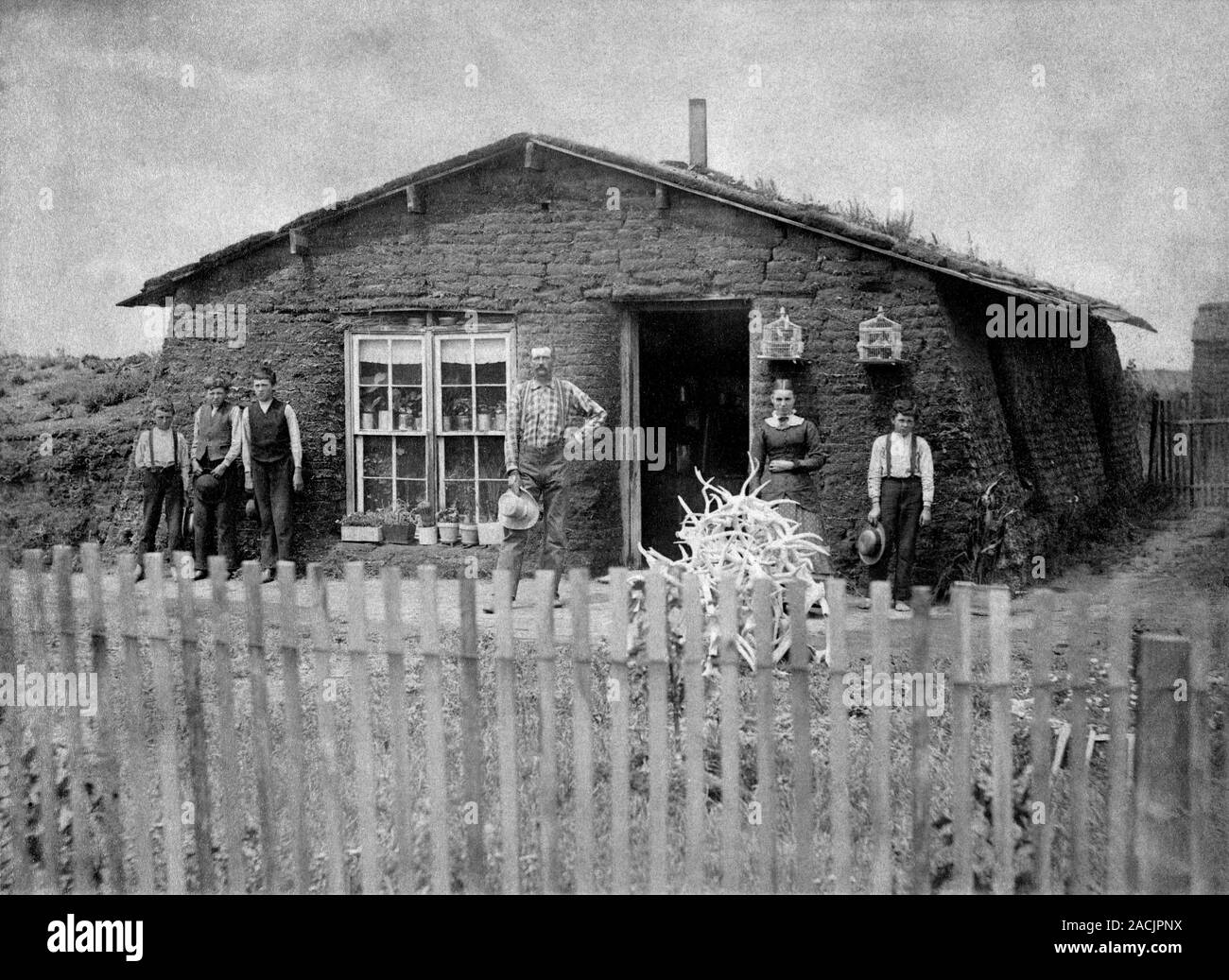 Sod house. 19thcentury American family standing in front of their sod