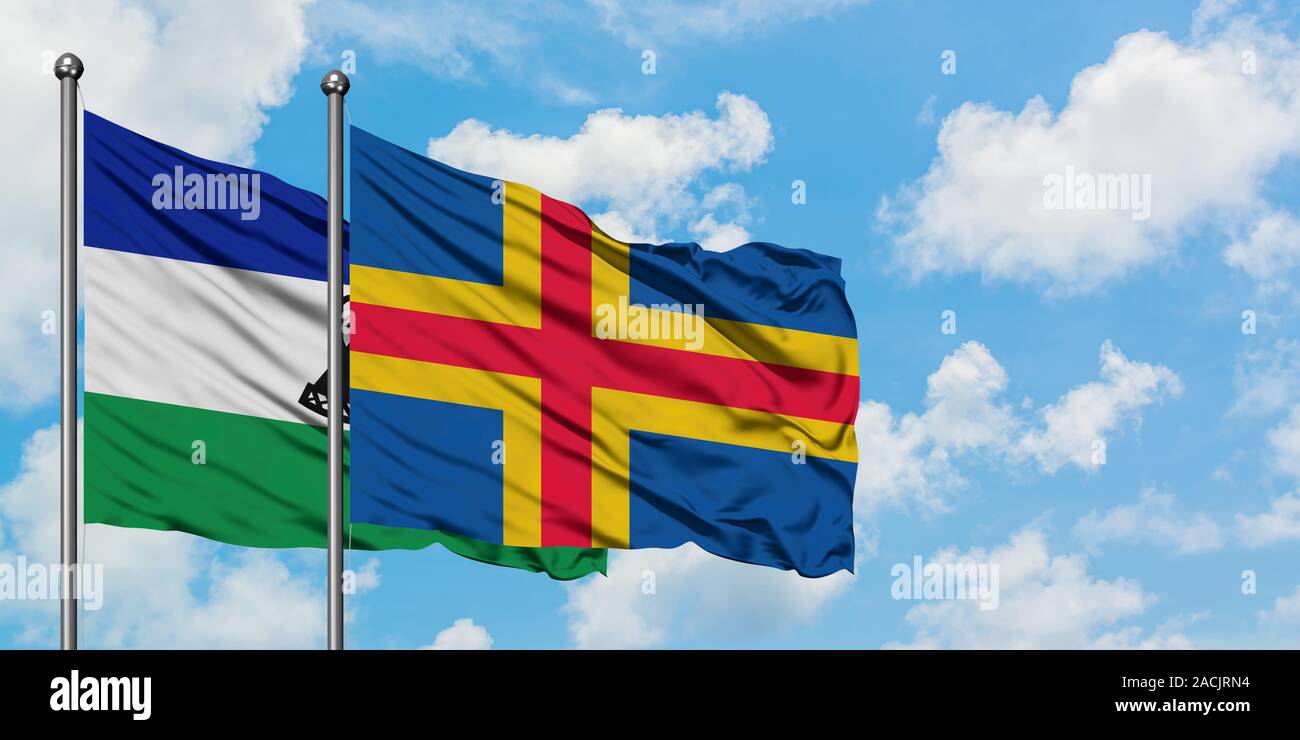 Lesotho and Aland Islands flag waving in the wind against white cloudy ...