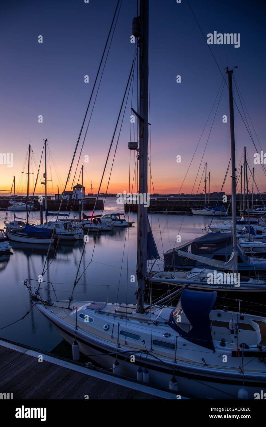 Boats moored in Victoria Dock, Caernarfon, North Wales at dusk Stock Photo