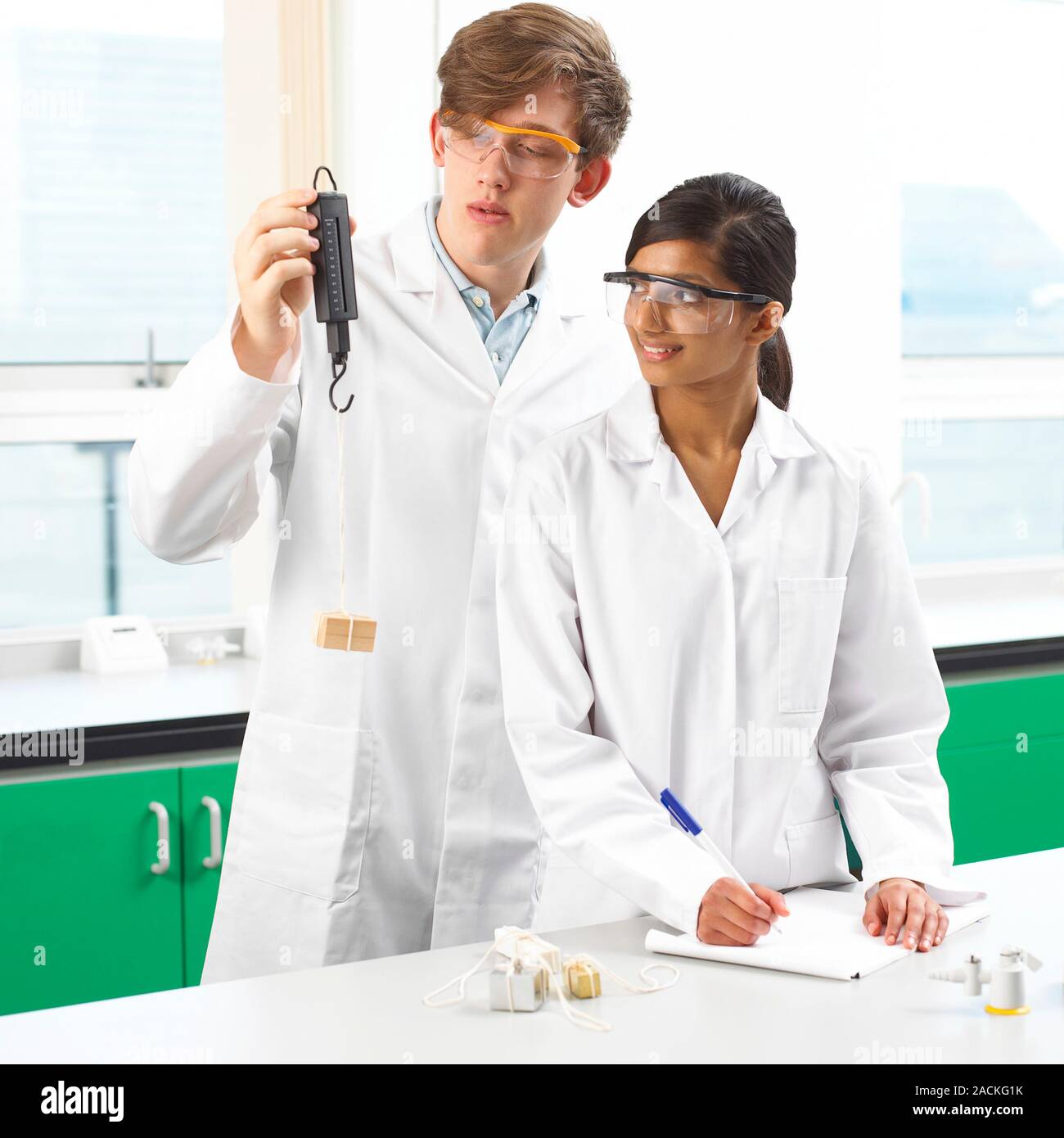 Weight measurement. Students using a spring balance (or spring scale