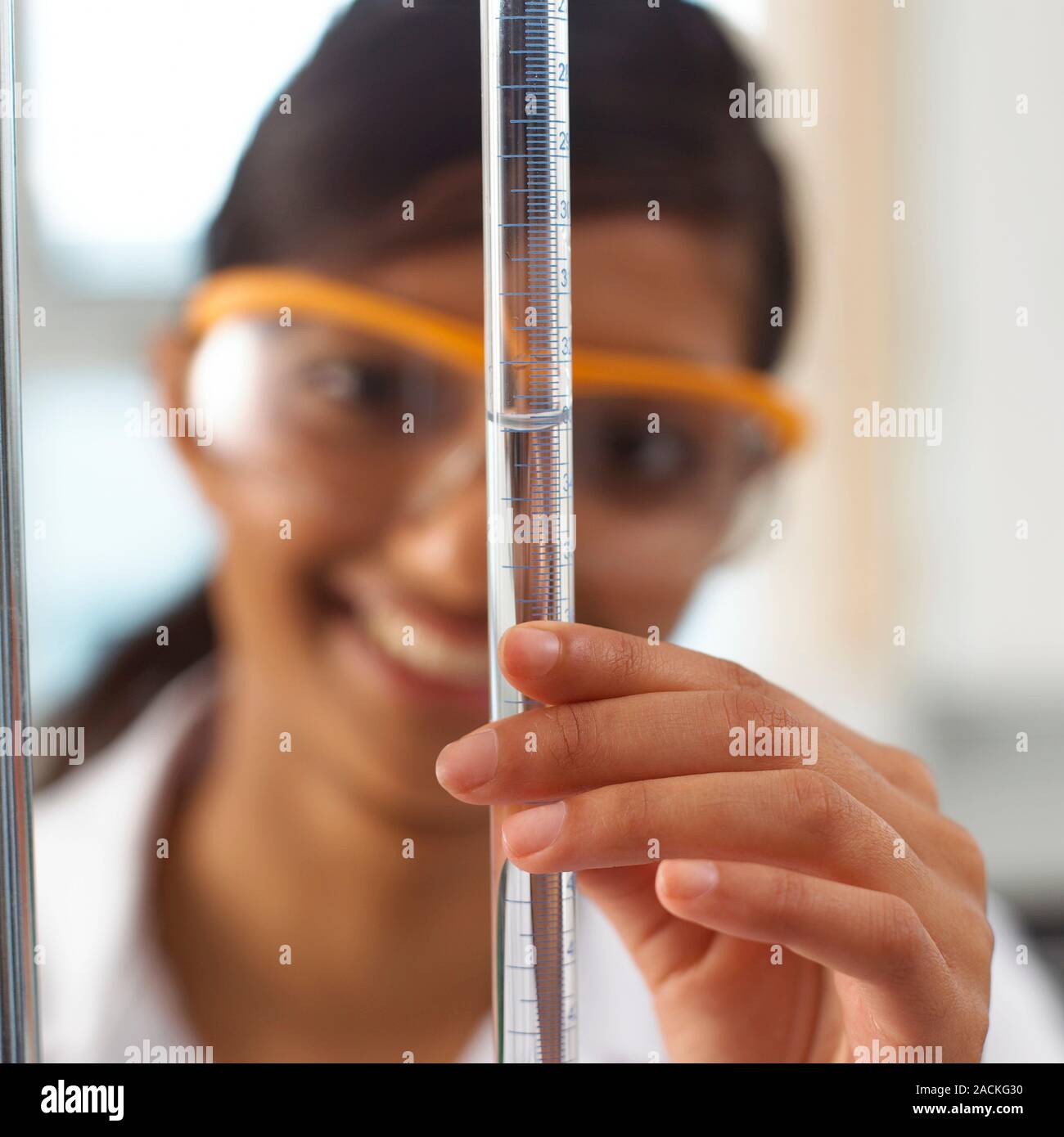 Titration experiment. Student taking a volume reading from a burette