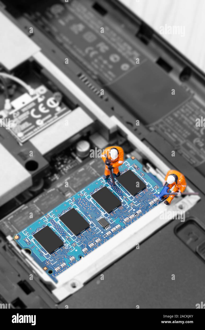 Miniature scale model construction workers installing RAM into the memory slot on a laptop computer Stock Photo
