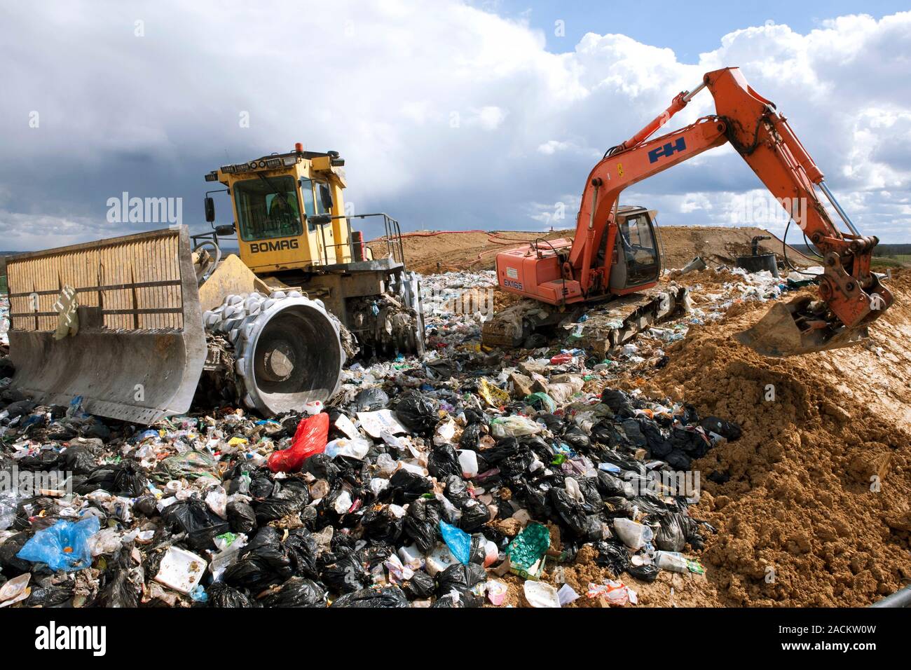 Landfill site. Vehicles compacting and covering waste with soil at a