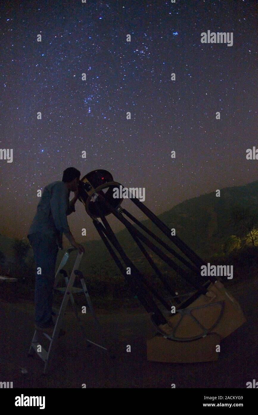 Observer using a Dobsonian telescope at night. The Dobsonian telescope