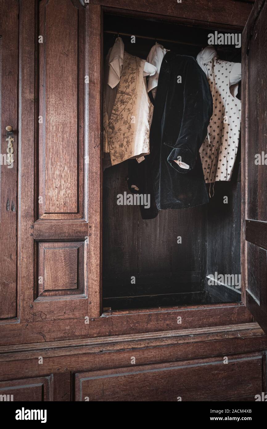 A velvet smoking jacket and waistcoats hanging up in a wardrobe at Chastleton House, Oxfordshire. Stock Photo
