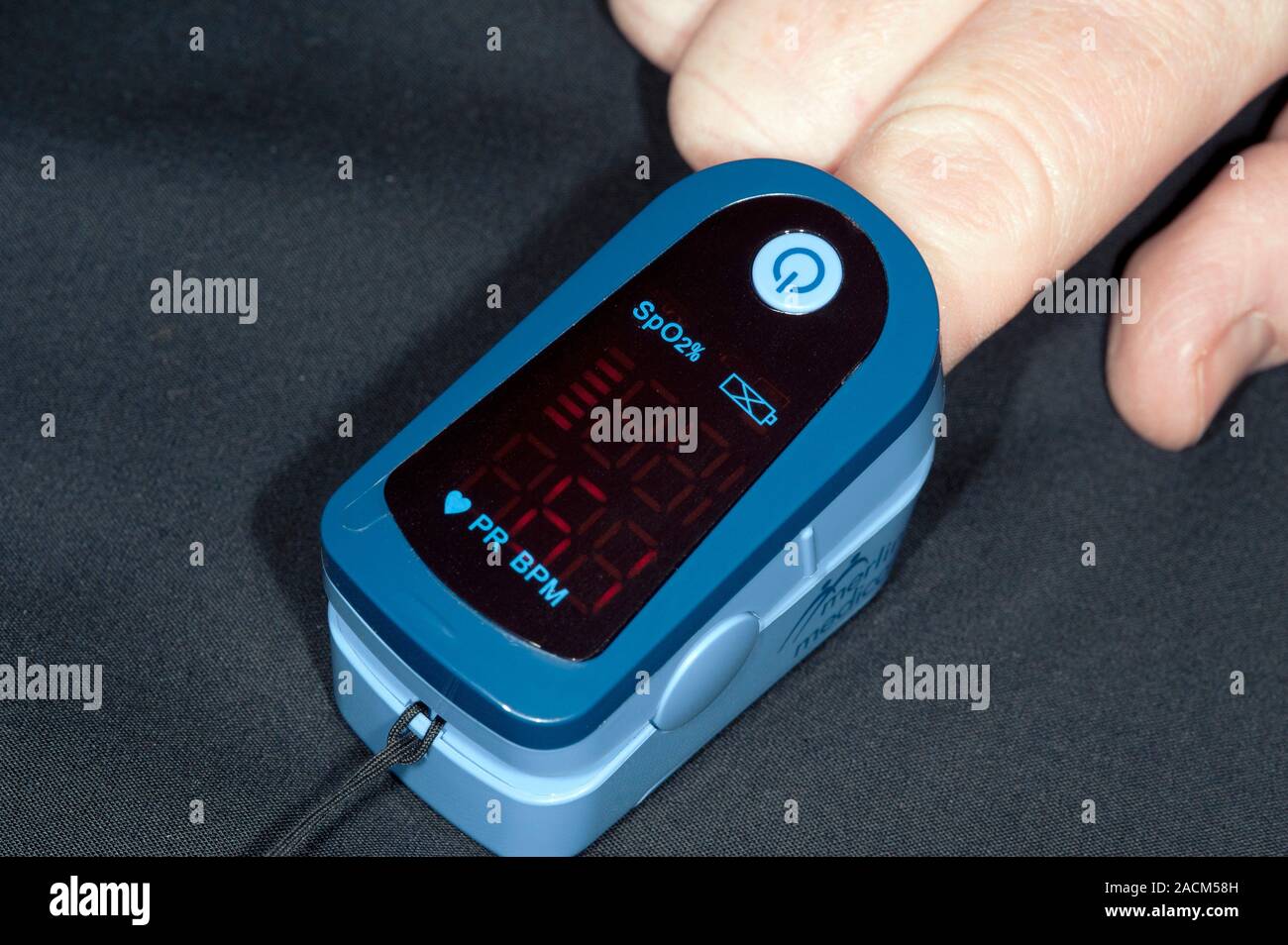 Adult pulse oximeter (blood oxygen meter) fitted to the finger of an adult to measure pulse rate