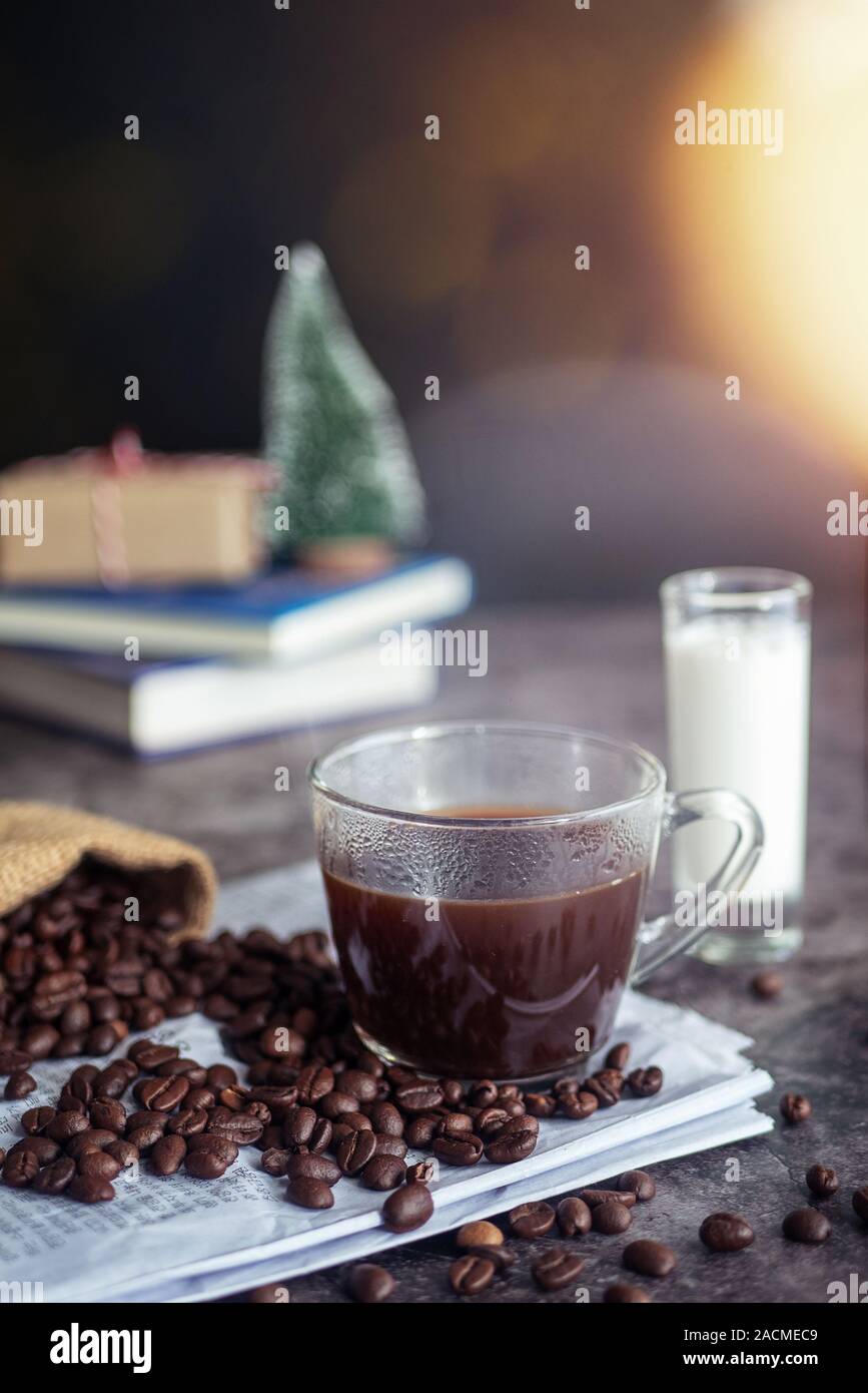 a cup of hot espresso coffee drink with smoke and roasted coffee beans on the table in the morning. vertical image, cropped shot Stock Photo