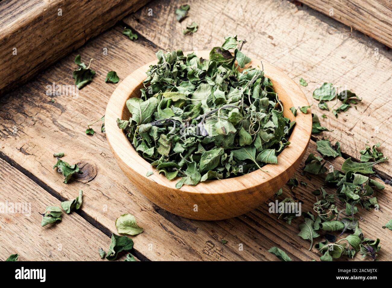 Bowl of dried oregano leaves on wooden background.Dried oregano