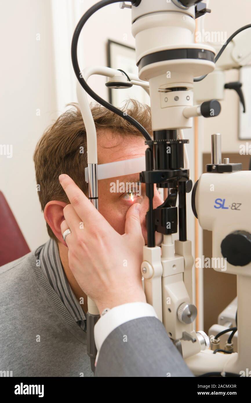 Eye examination. Doctor using a slitlamp ophthalmoscope to examine a patient's eyes. This