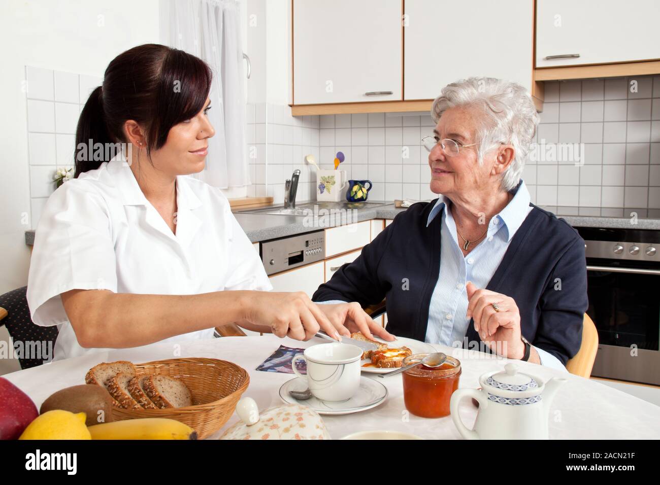 Caregiver helps senior citizen with breakfast Stock Photo