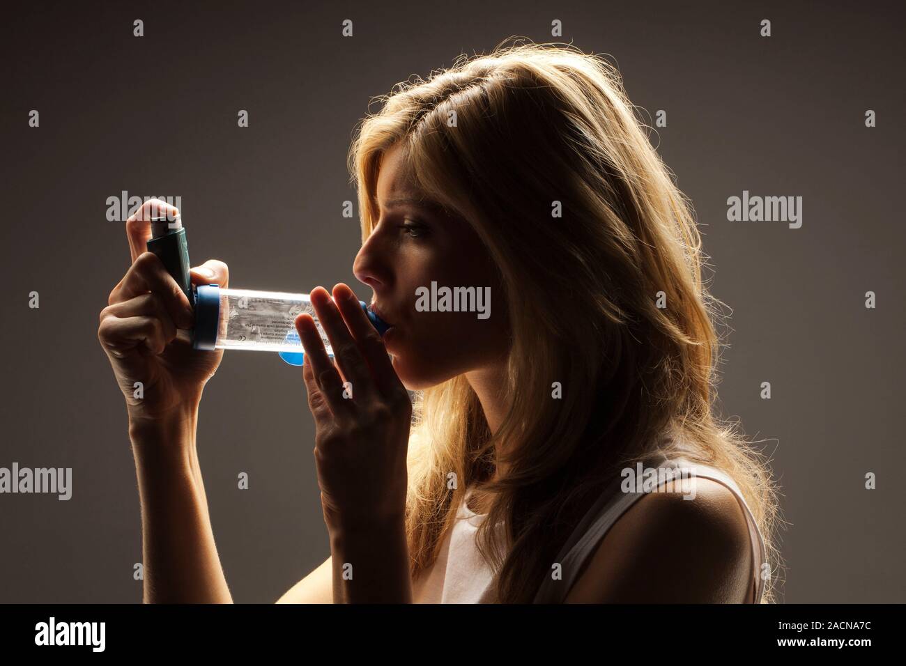 Asthma inhaler with spacer device used by a female patient. The inhaler with volumetric spacer
