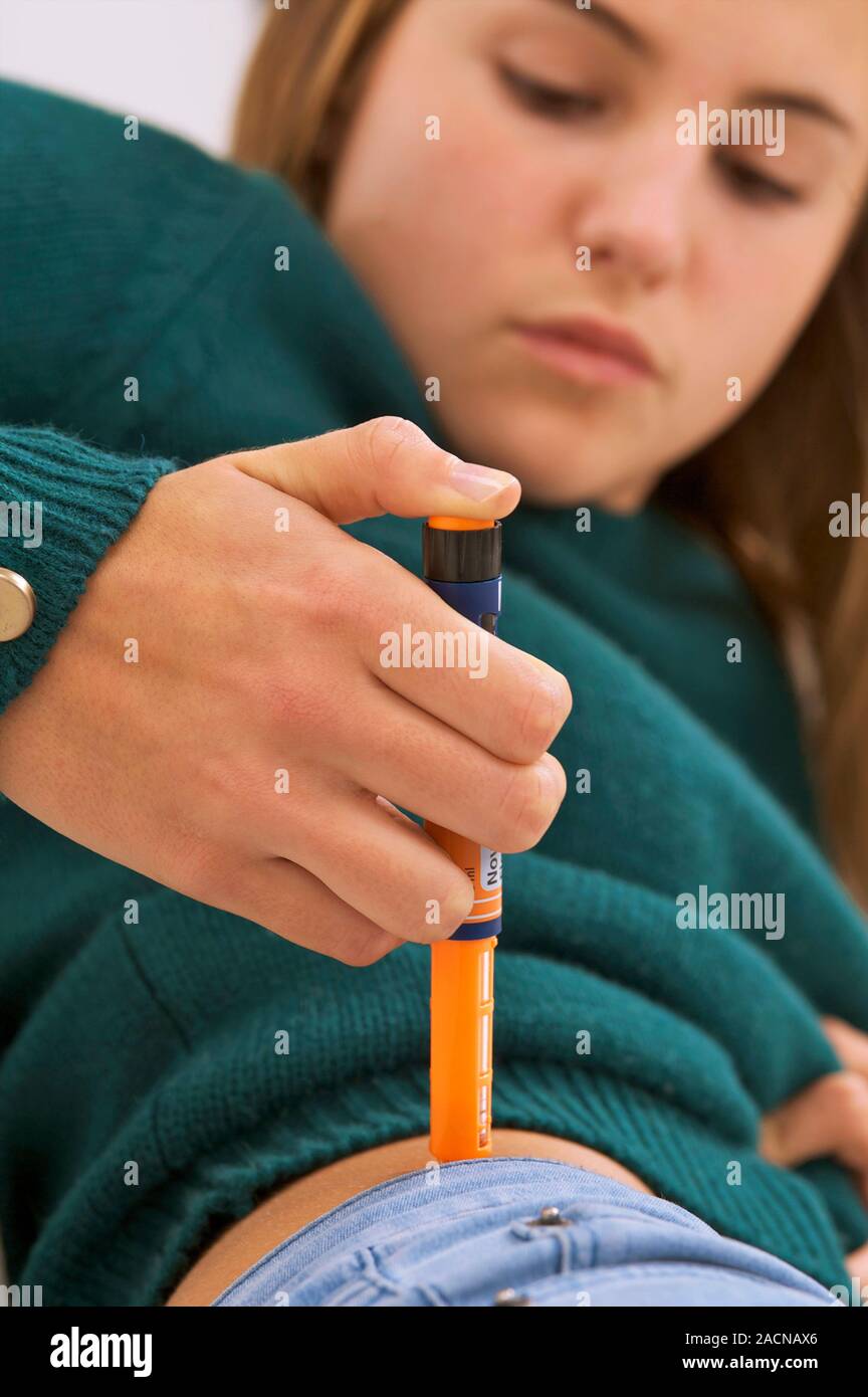 Insulin injection. Diabetic teenage girl injecting herself in the