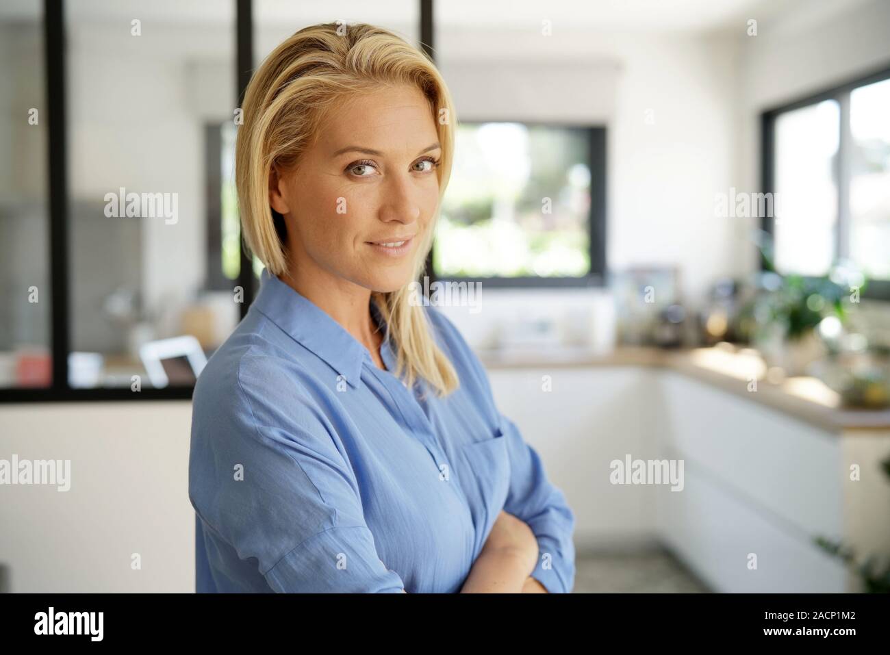 Attractive blond woman standing with arms crossed Stock Photo - Alamy