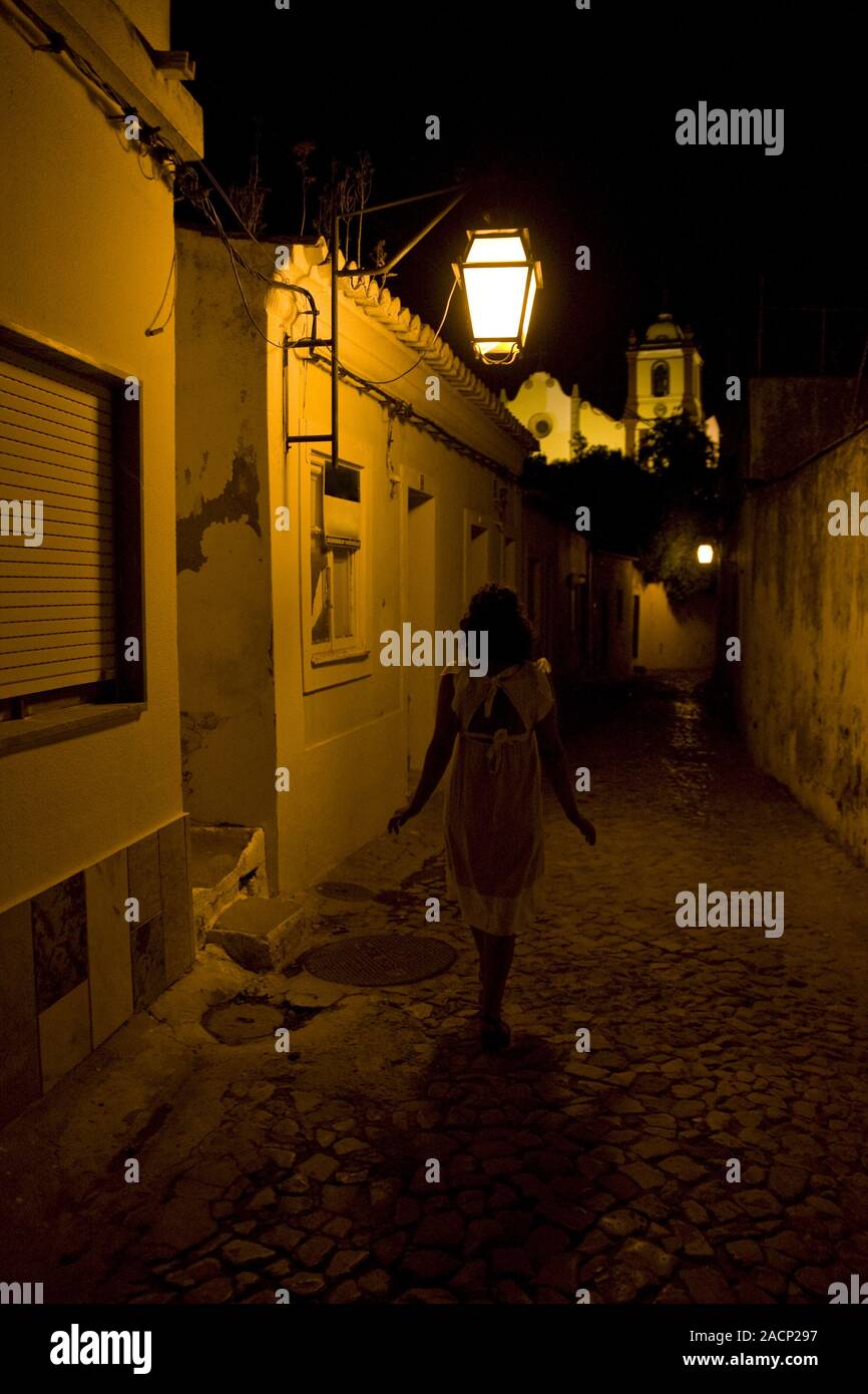 Girl in white walking down a street at night Stock Photo - Alamy