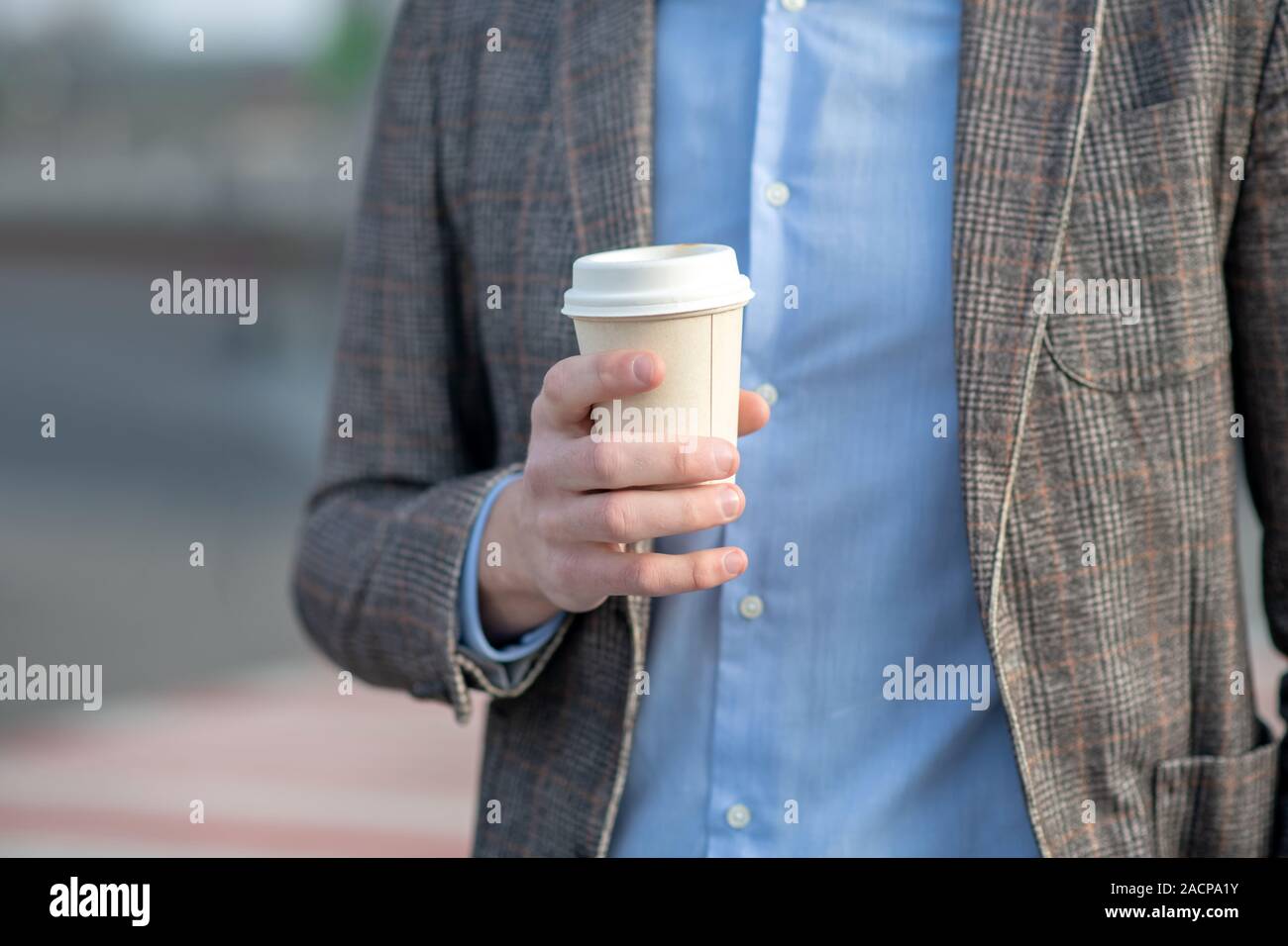 Man in a blue shirt holding a cup of coffee Stock Photo