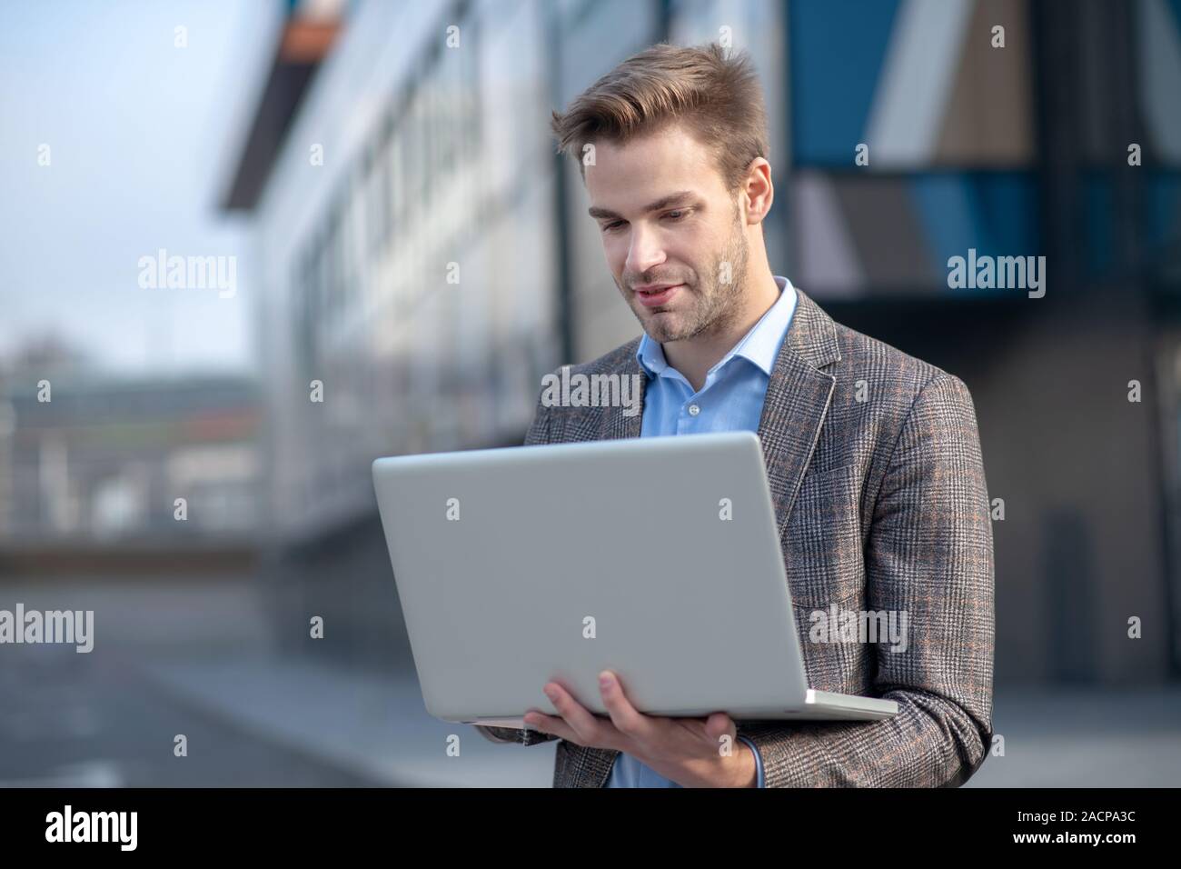 Young man in a blue shirt holding a laptop Stock Photo