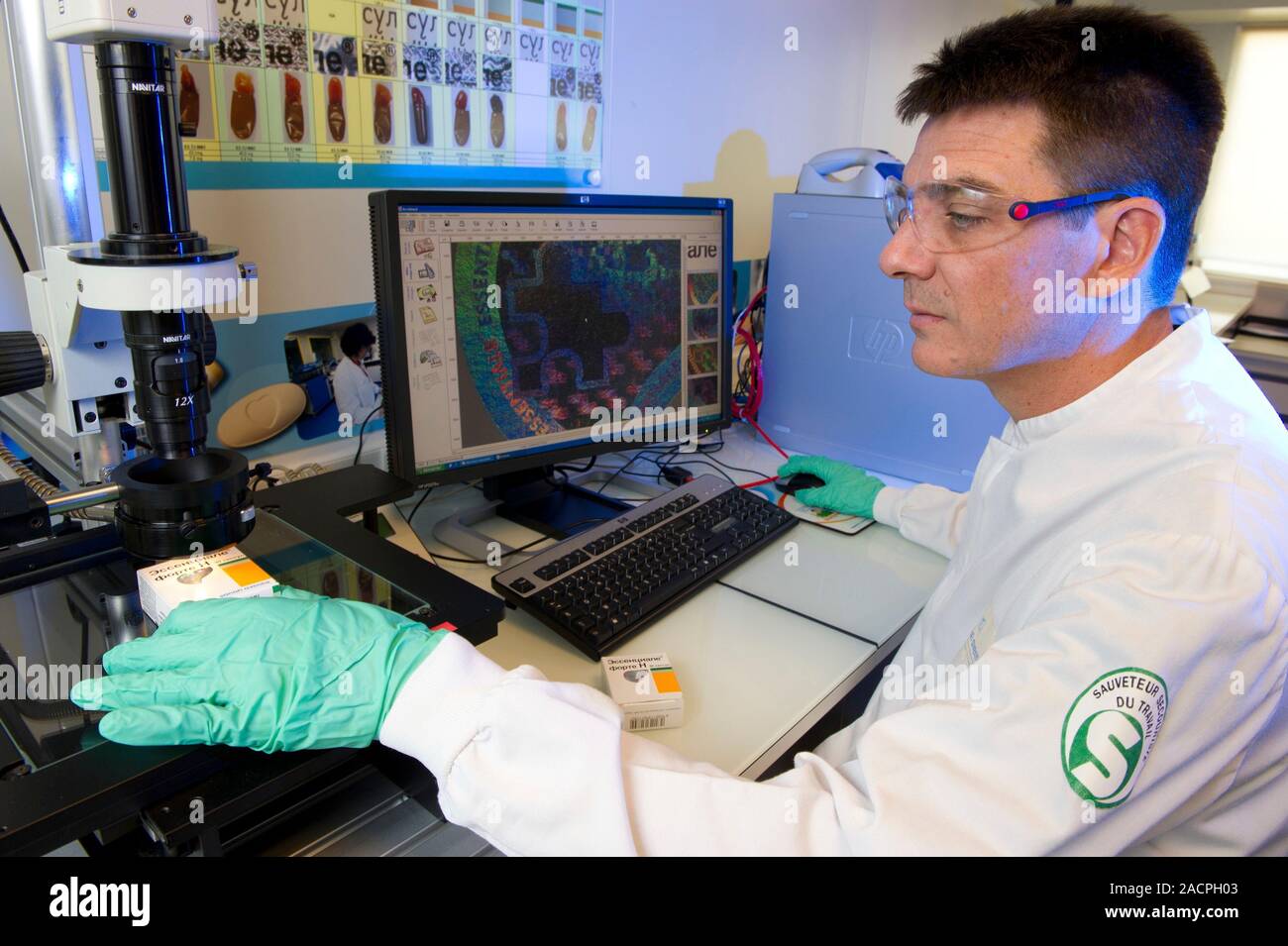 Counterfeit drugs analysis. Laboratory worker analysing the hologram on ...