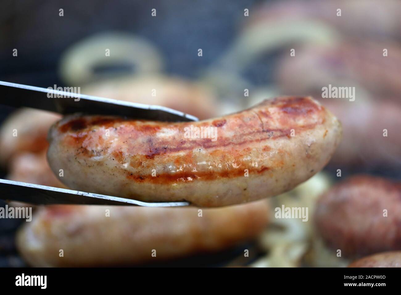 A pork sausage barbecued and barbecue tongs Stock Photo