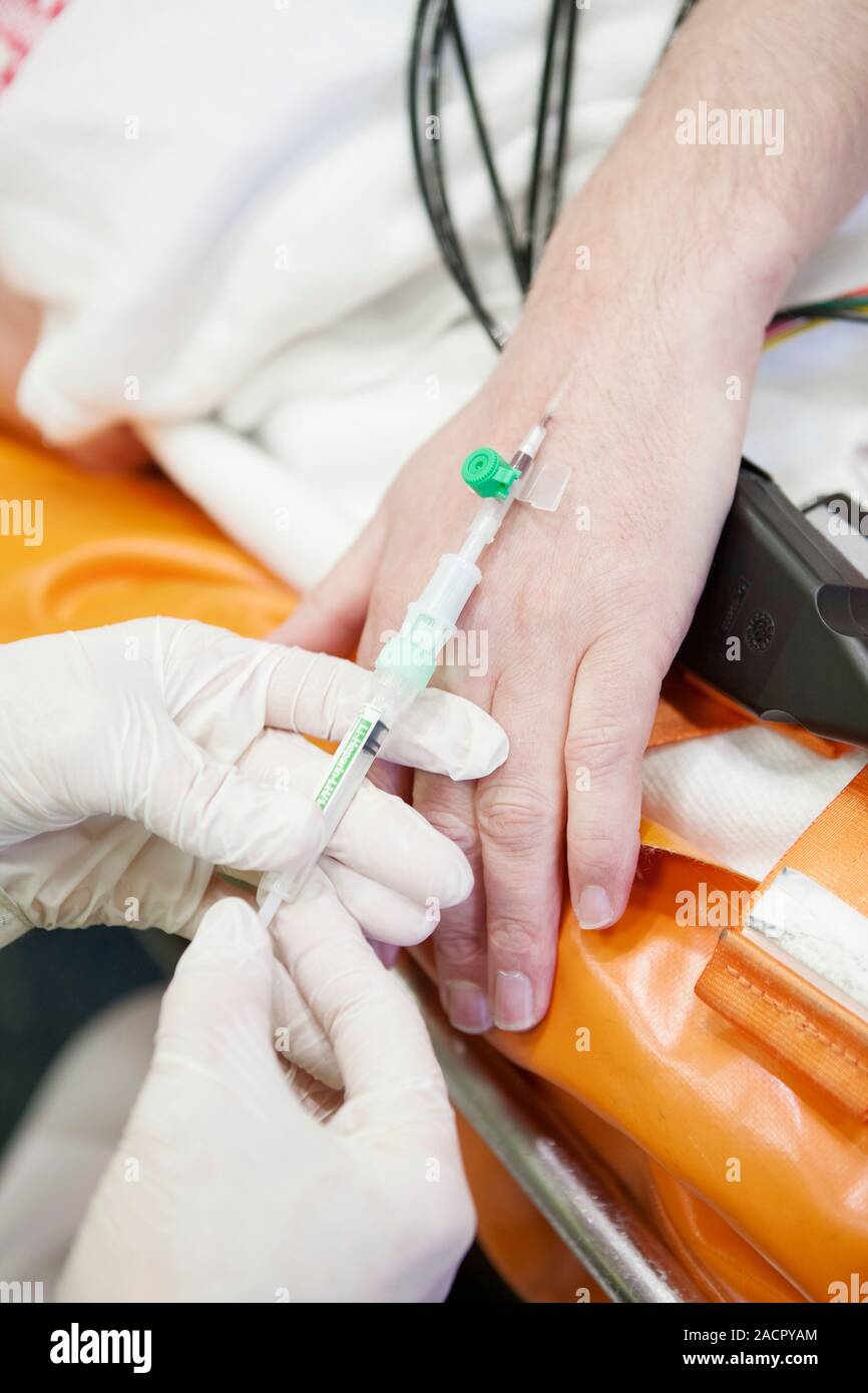 Cardiac patient in an ambulance. Paramedic administering an injection ...