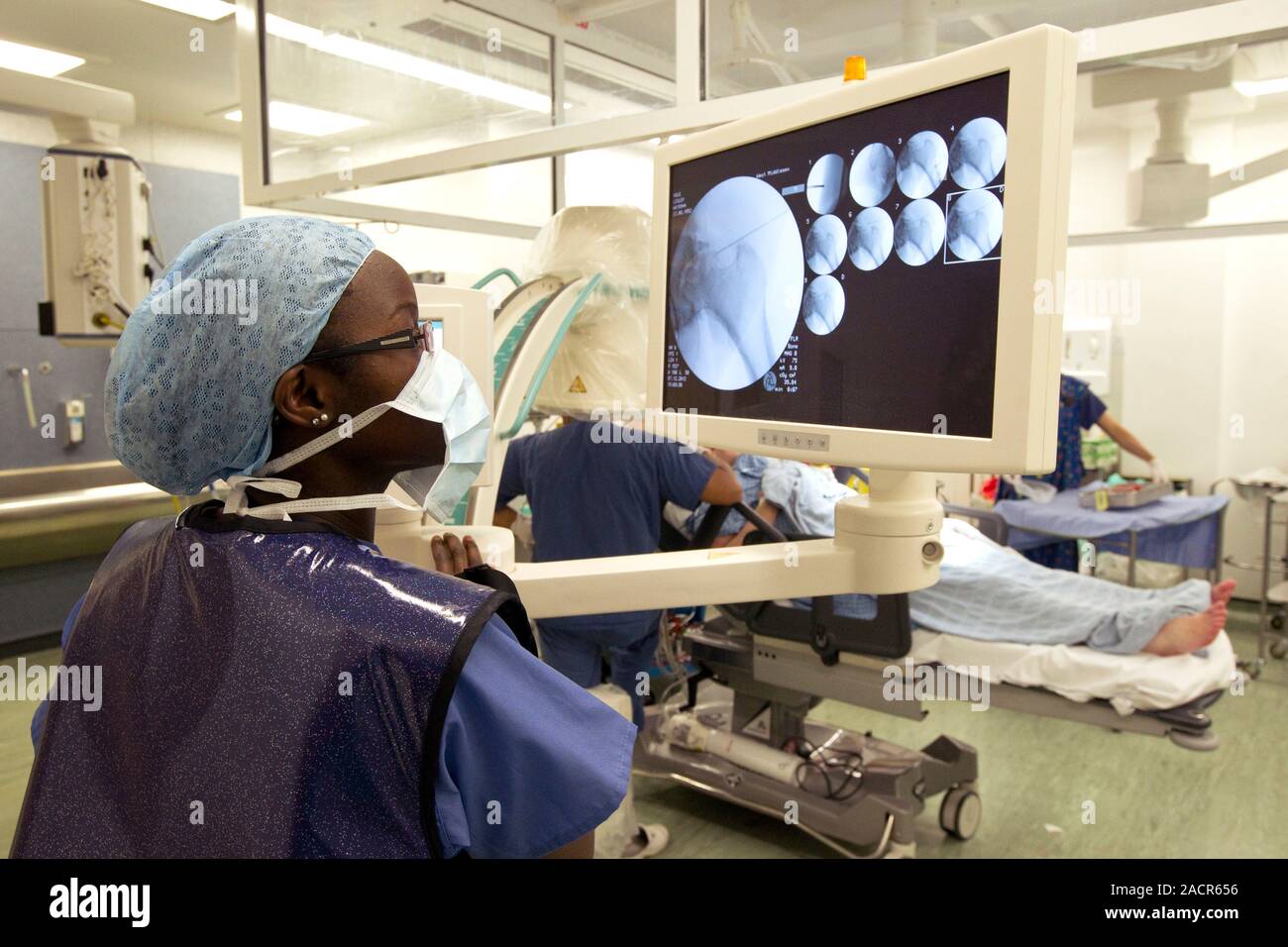Hip fracture surgery. Radiographer checking an X0ray of a patient with