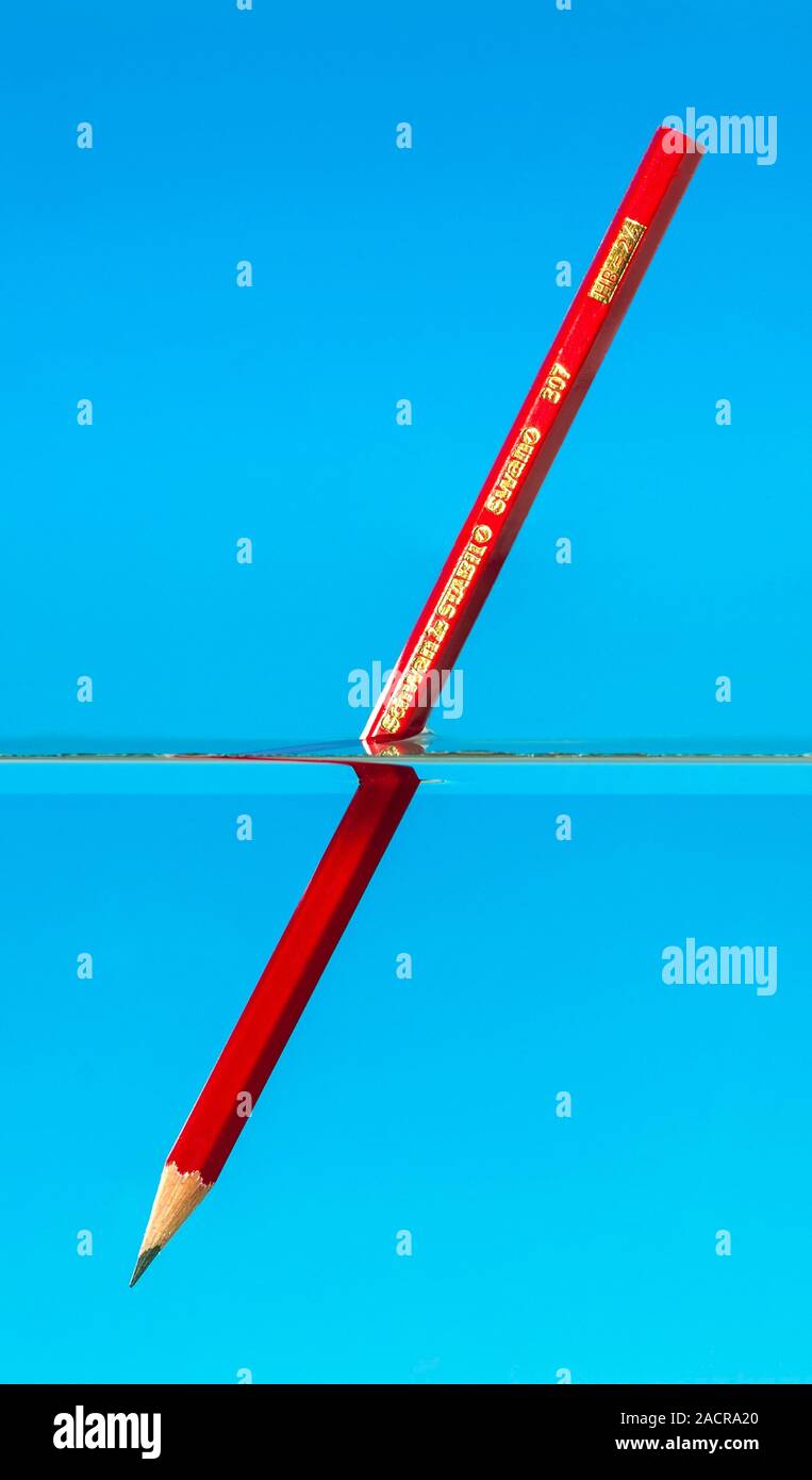 Light refraction experiment. Pencil in water being used to demonstrate