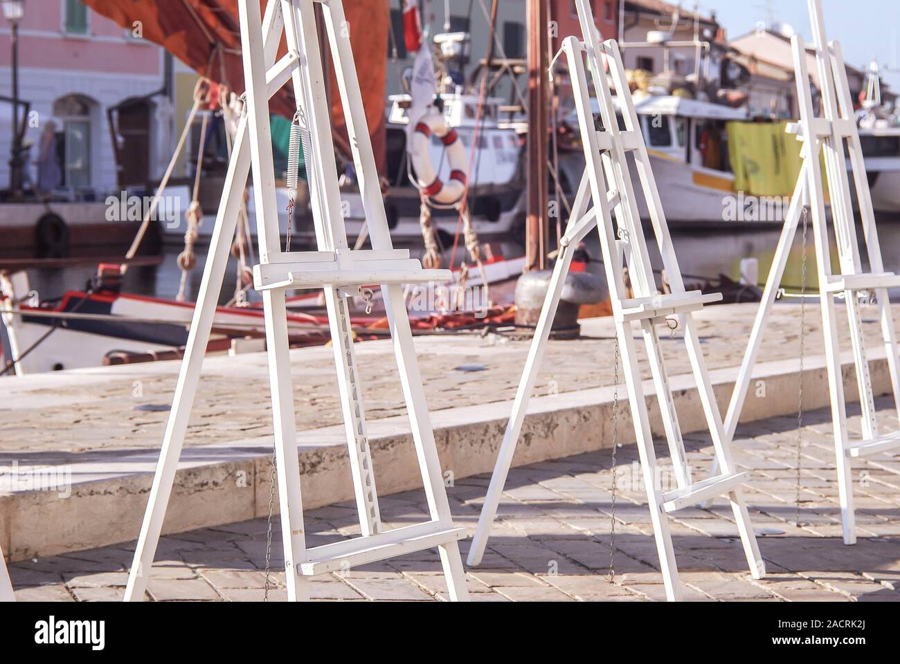 Easels For Artists Against The Backdrop Of The Canal And Yachts