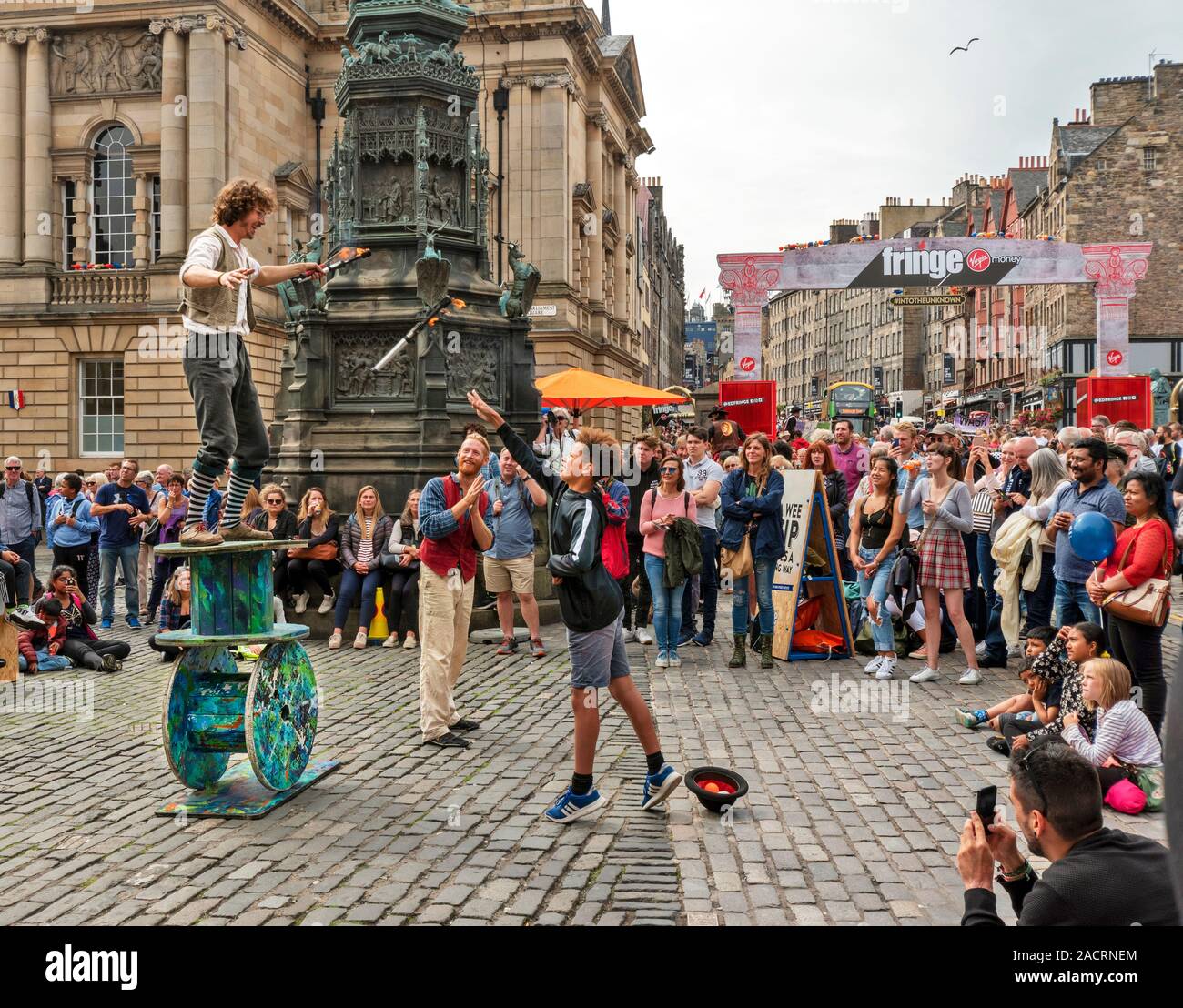 EDINBURGH SCOTLAND THE FRINGE STREET PERFORMERS A BALANCING ACT AND YOUNG MEMBER OF THE PUBLIC THROWING A FLAMING TORCH TO THE PERFORMER Stock Photo