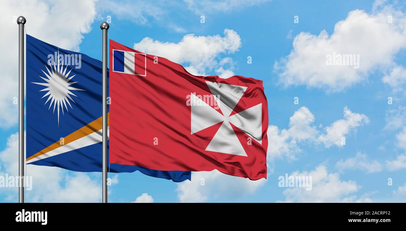 Marshall Islands and Wallis And Futuna flag waving in the wind against white cloudy blue sky together. Diplomacy concept, international relations. Stock Photo