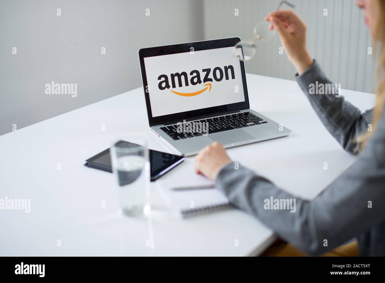 Young woman using laptop with Amazon logo in the screen seeting at the  office desk. A buissineswoman with the laptop with Amazon logo Stock Photo  - Alamy