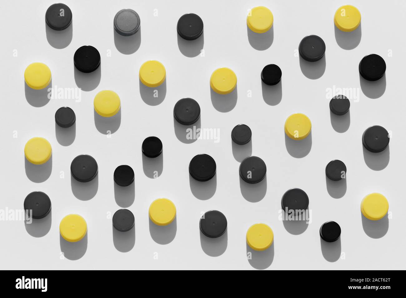 Plastic bottle caps background with black and yellow color random pattern on white background Stock Photo
