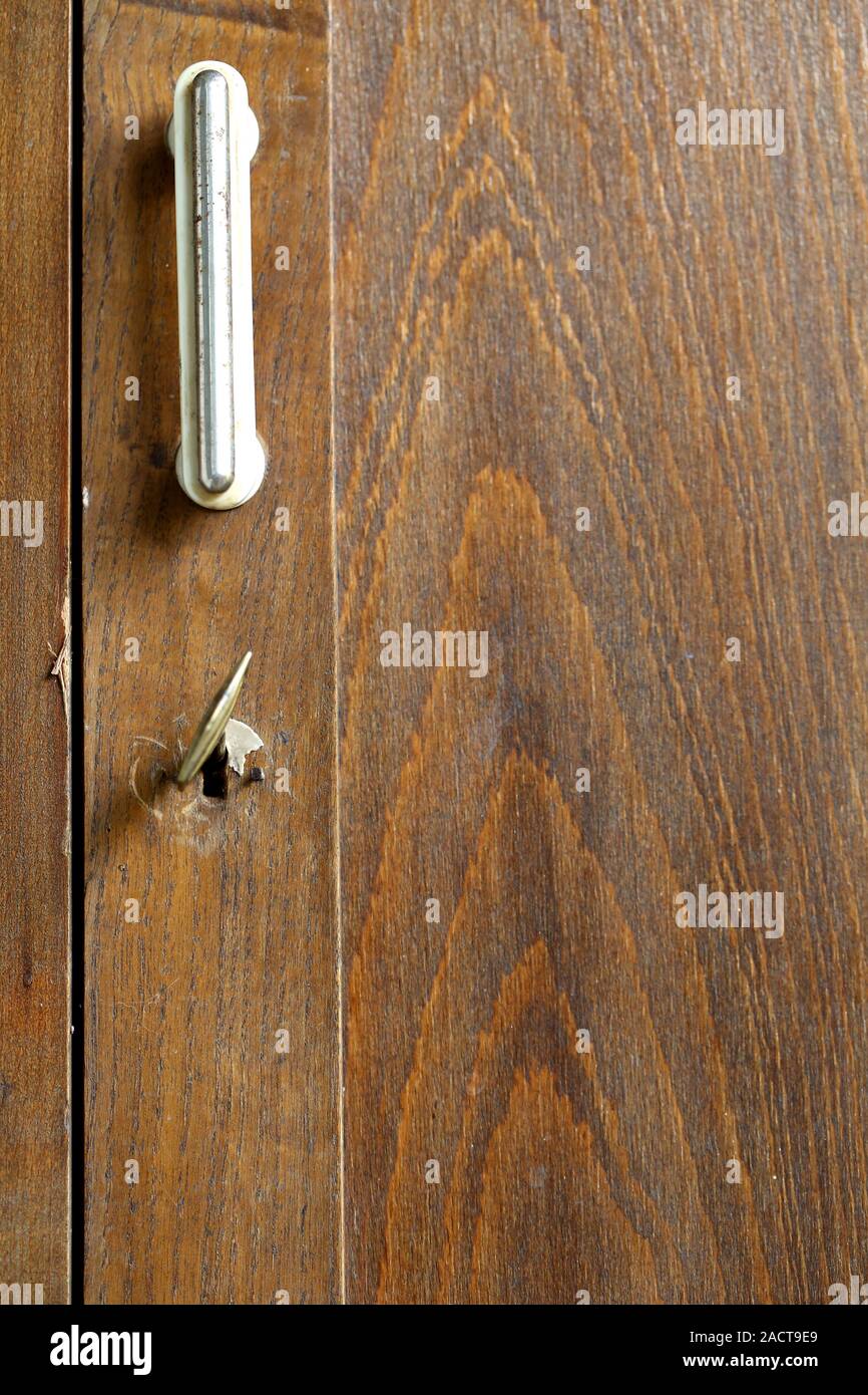 Handle and keyhole with a key of an old wardrobe. Stock Photo
