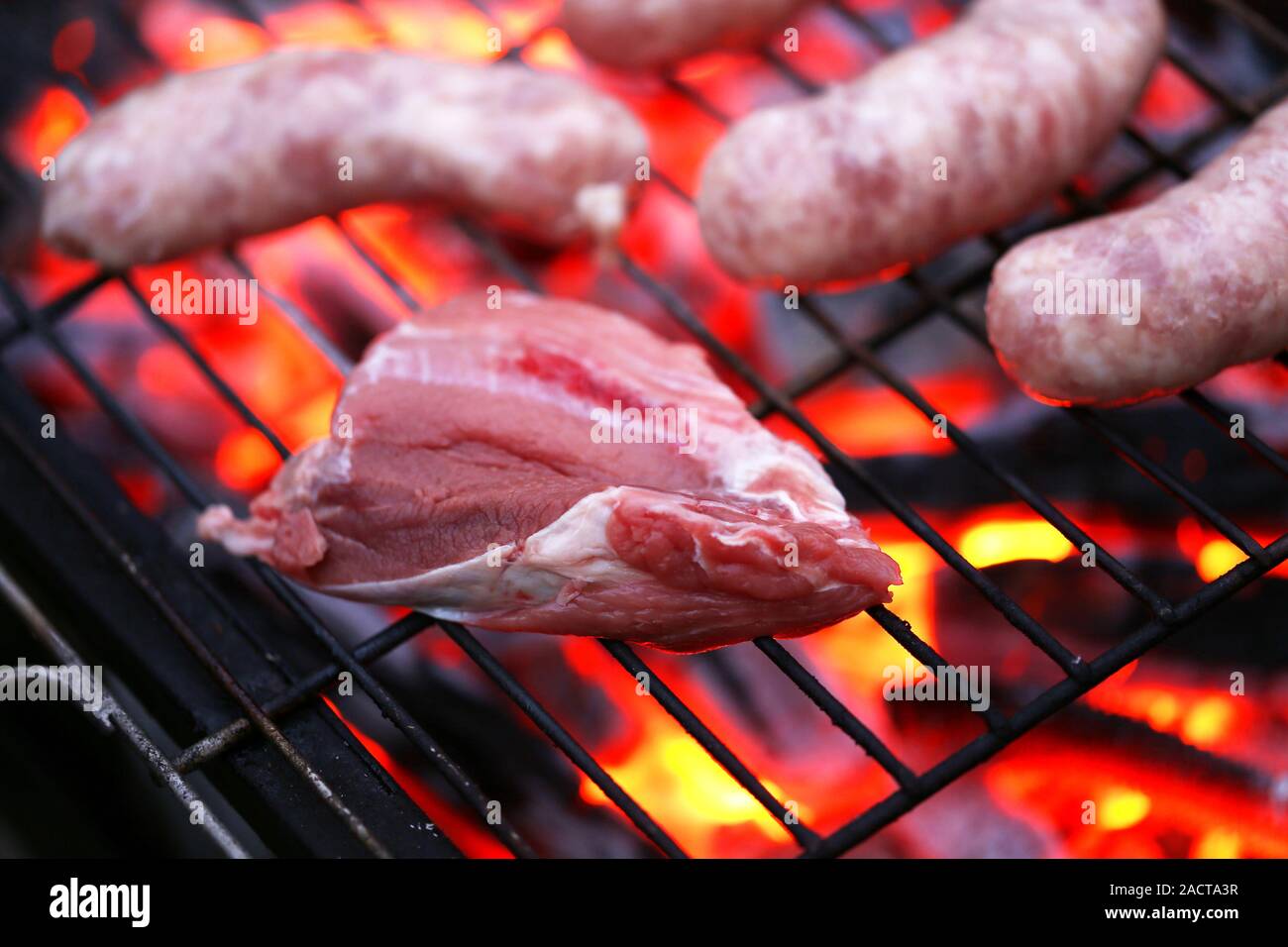 Raw meat and sausages on BBQ. Stock Photo