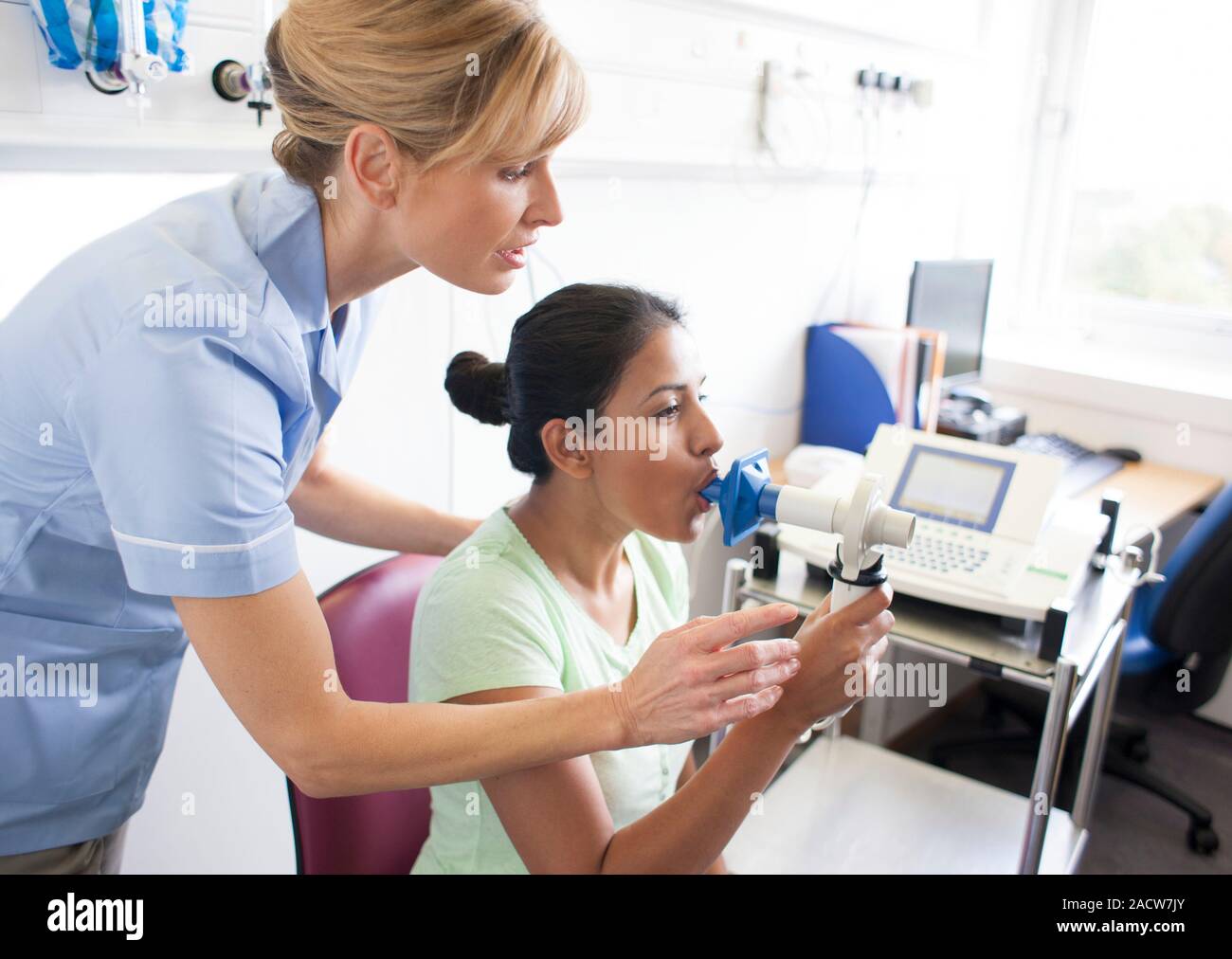 Lung function test. Nurse watching as a patient blows into a peak flow