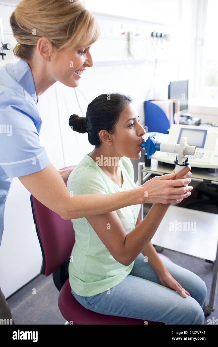 Lung function test. Nurse watching as a patient blows into a peak flow