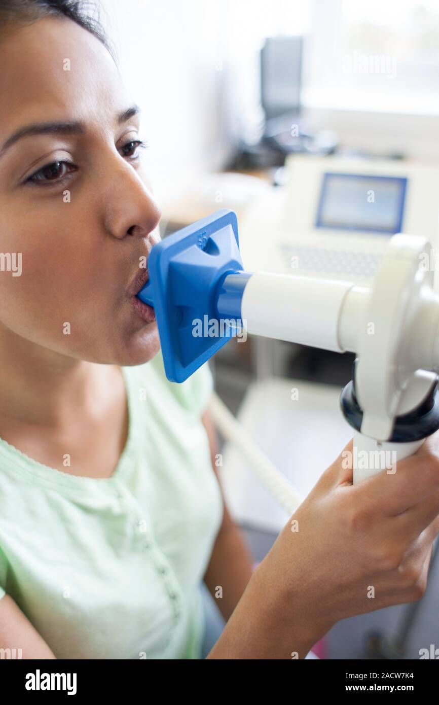 Lung function test. Patient blowing into a peak flow spirometer during