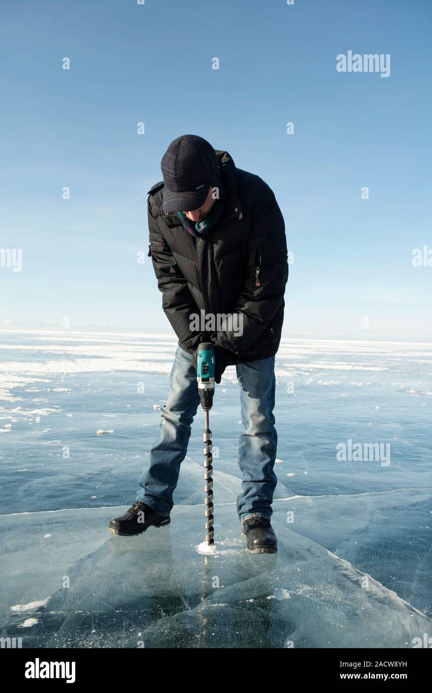 Ice thickness measuring, Lake Baikal, Russia. Man drilling into