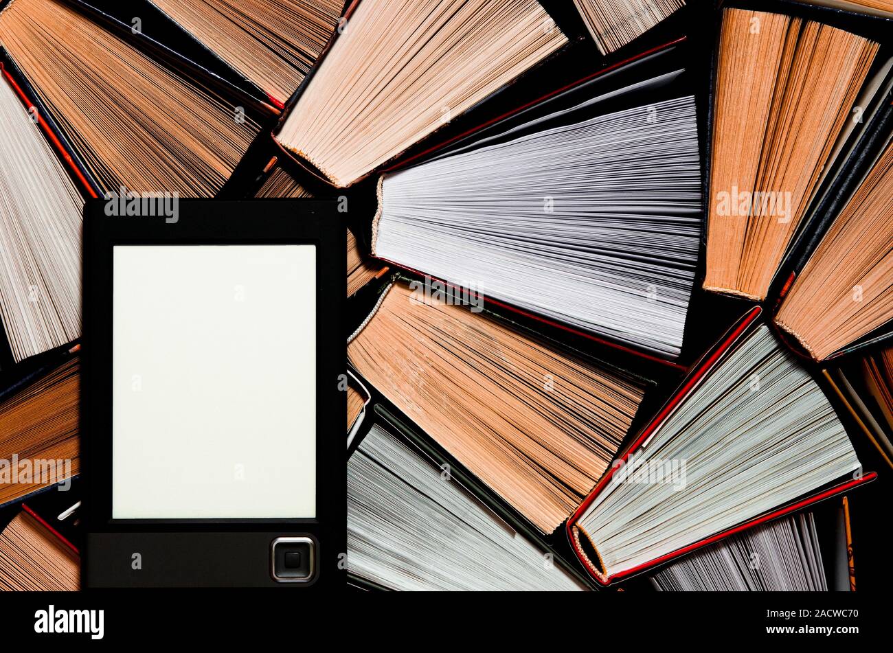 The e-book with a clean white screen rests on the open multi-colored books. ready to read Stock Photo