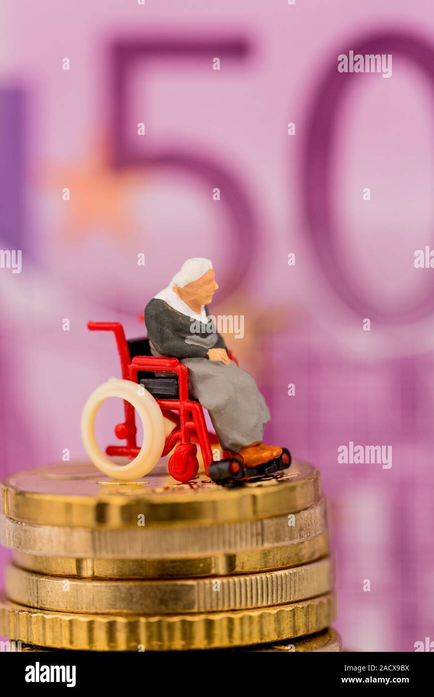 Woman in a wheelchair on a pile of money Stock Photo