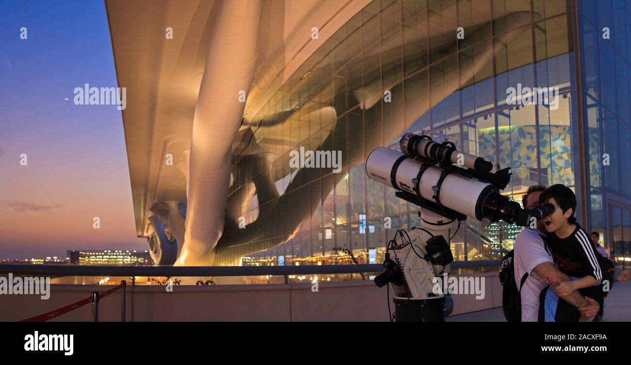 Child looking through a telescope pointing at the Moon. Photographed at