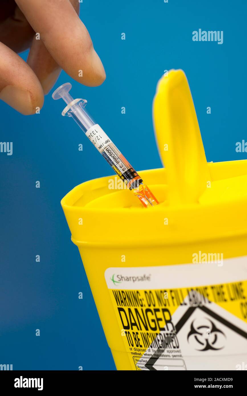 Safe disposal of a hypodermic syringe into a sharps bin. Closeup of a
