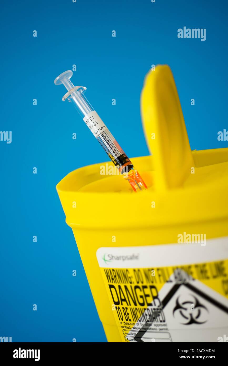 Safe disposal of a hypodermic syringe into a sharps bin. Closeup of a