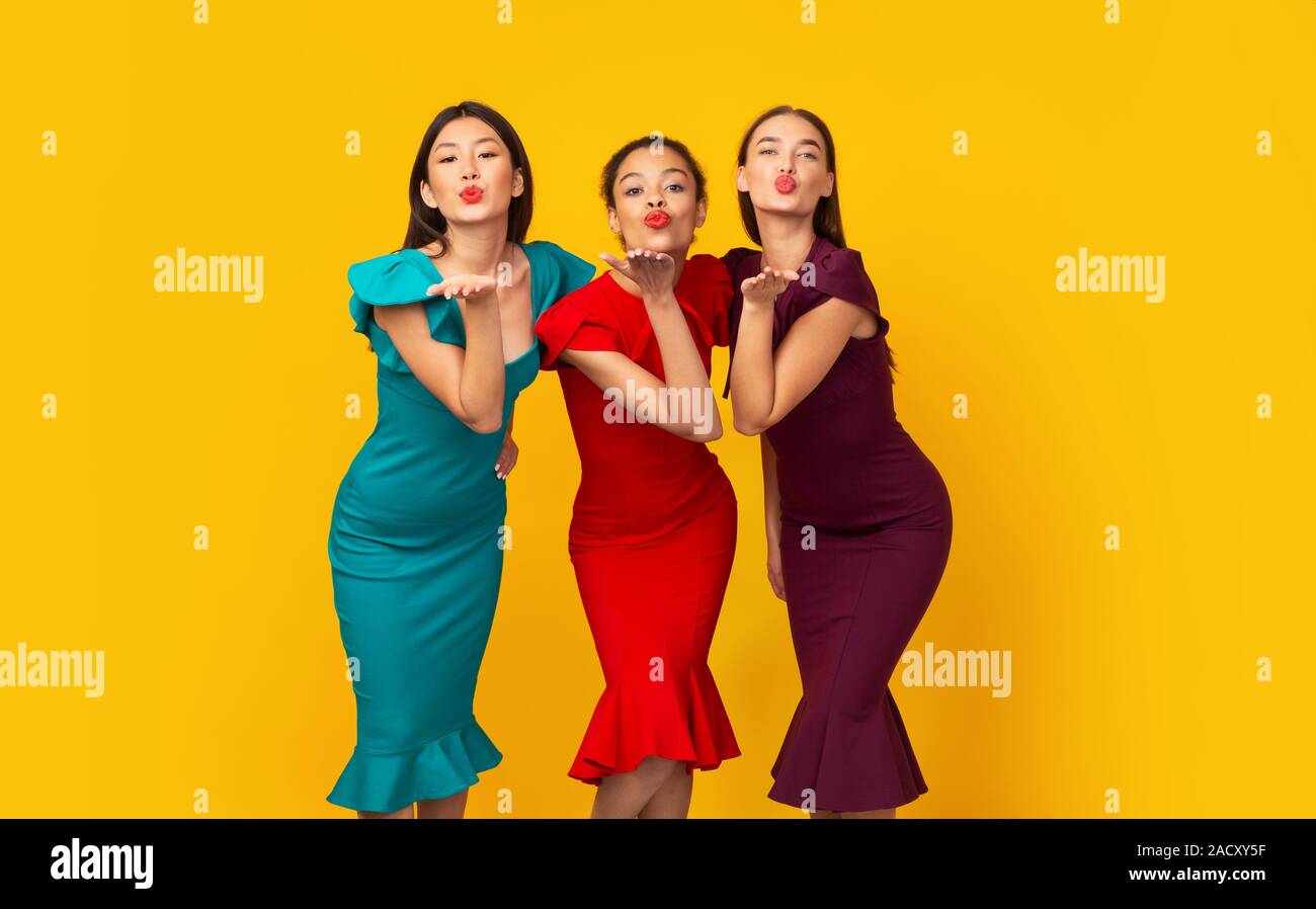 Three Diverse Girls In Dresses Sending Air Kiss, Studio Shot Stock Photo
