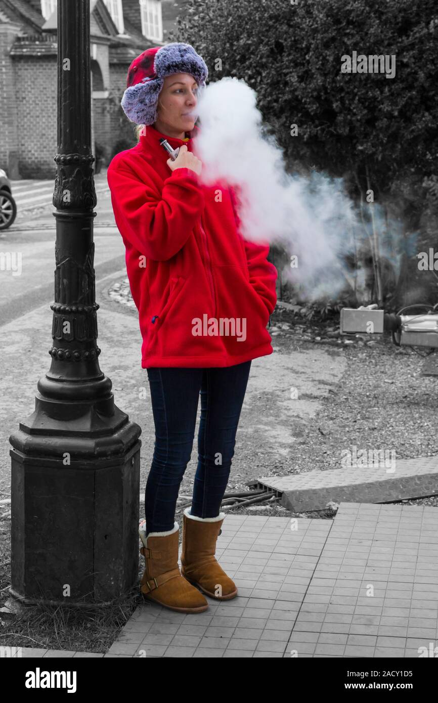 Woman vaping at Winchester, Hampshire, UK in November - selective colour colouring, colour popping Stock Photo