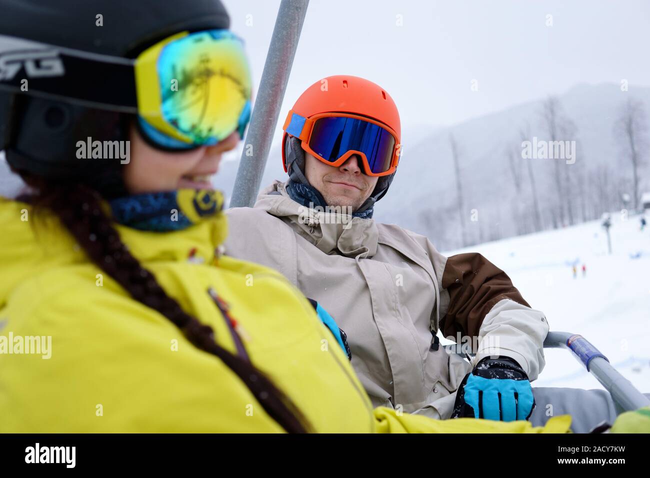 Couple sitting on chairlift in mountain resorts. Stock Photo