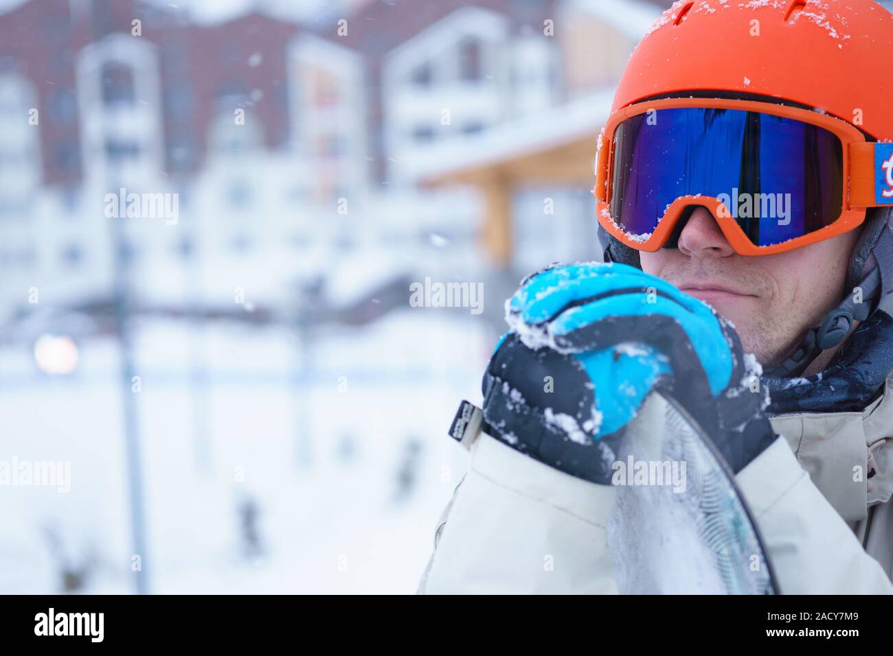 Man snowboarder wearing orange helmet, grey jacket, black and blue