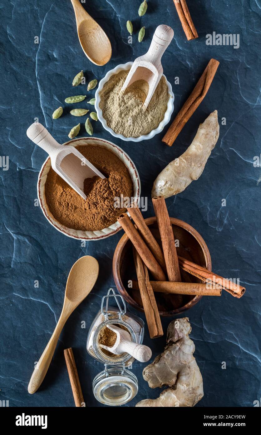 A top down view of a selection of complimentary Indian spices including cinnamon, ginger and cardamom in both ground powder form and whole form. Stock Photo