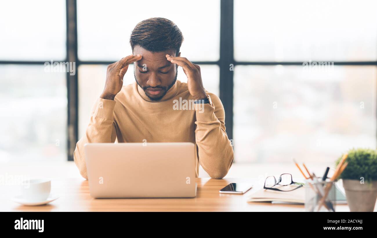 Exhausted millennial black businessman having migraine attack Stock Photo