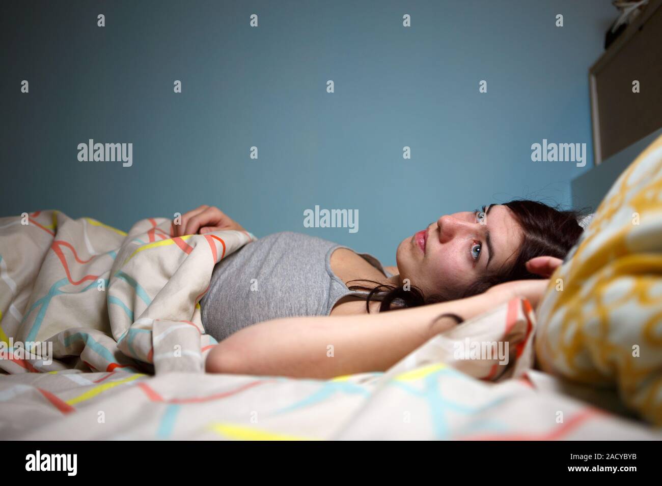 Young woman lying in bed suffering with insomnia  Noisy neighbour, stress, alarm sound, prevent from sleep concept Stock Photo