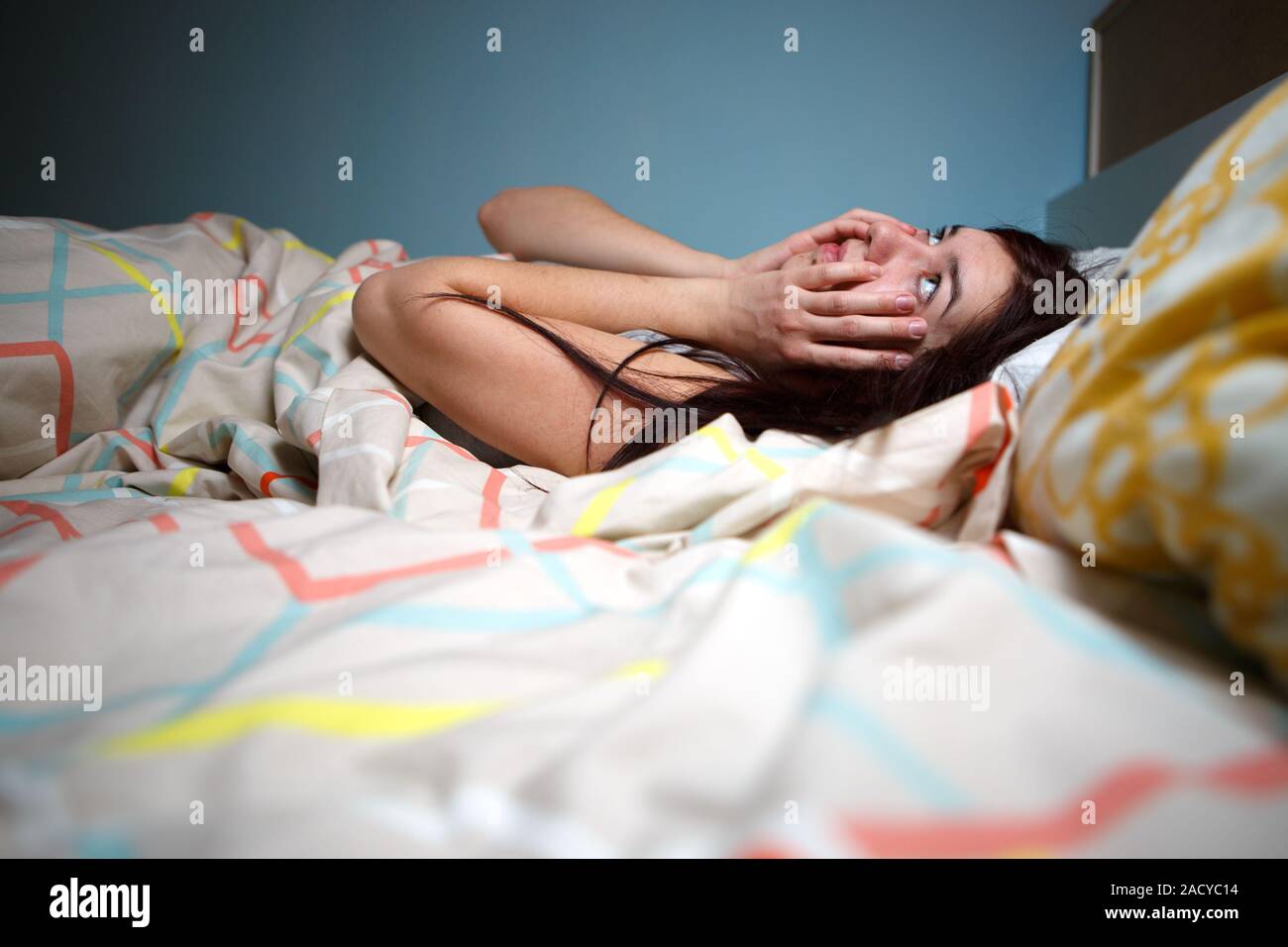Young woman lying in bed suffering with insomnia  Noisy neighbour, stress, alarm sound, prevent from sleep concept Stock Photo