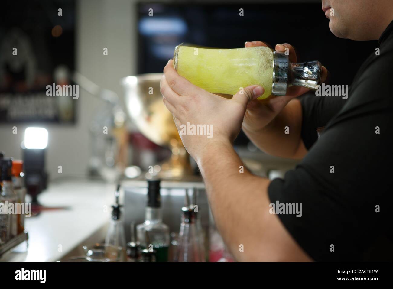 Bartender at work preparing cocktails. Shaking cocktail shaker Stock